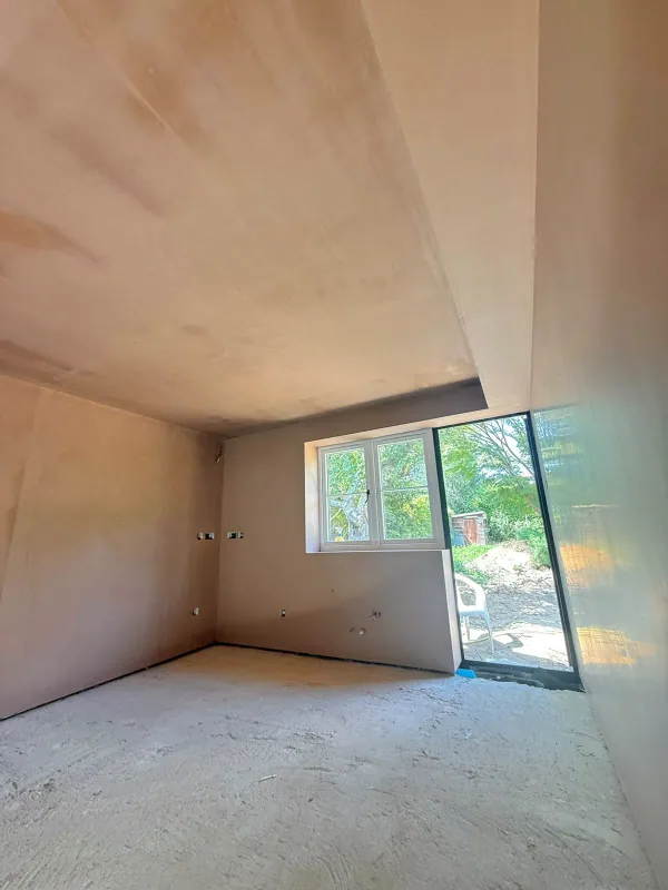 Fresh plaster to a room with a window, glazed door and ceiling bulkhead