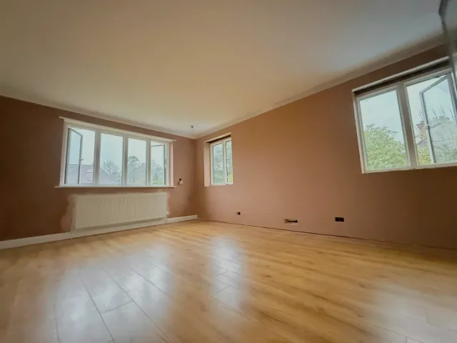 Freshly skimmed walls around three windows, with the existing floor and radiator retained